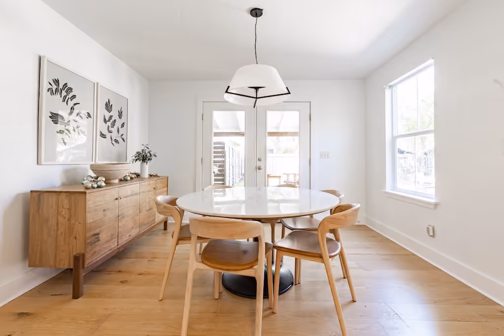 A bright dining room with wood furniture and botanical artwork